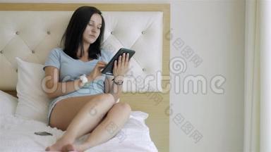 清晨躺在床上使用平板电脑的少女